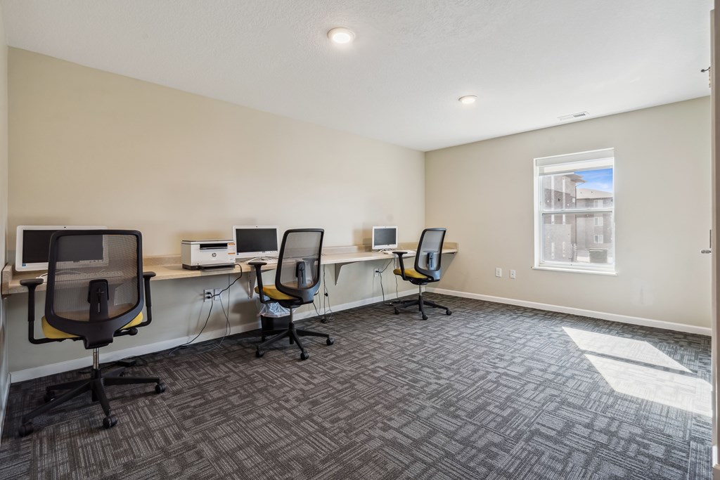 A room with four chairs and four computers.