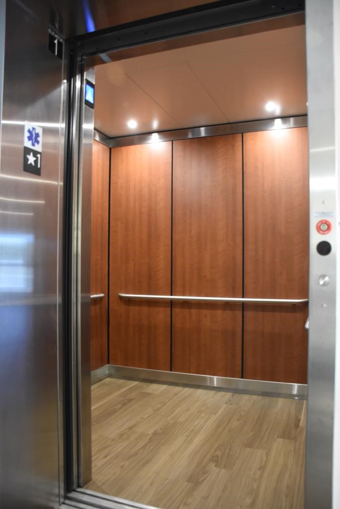 A metal elevator with a blue emergency sign on the wall.