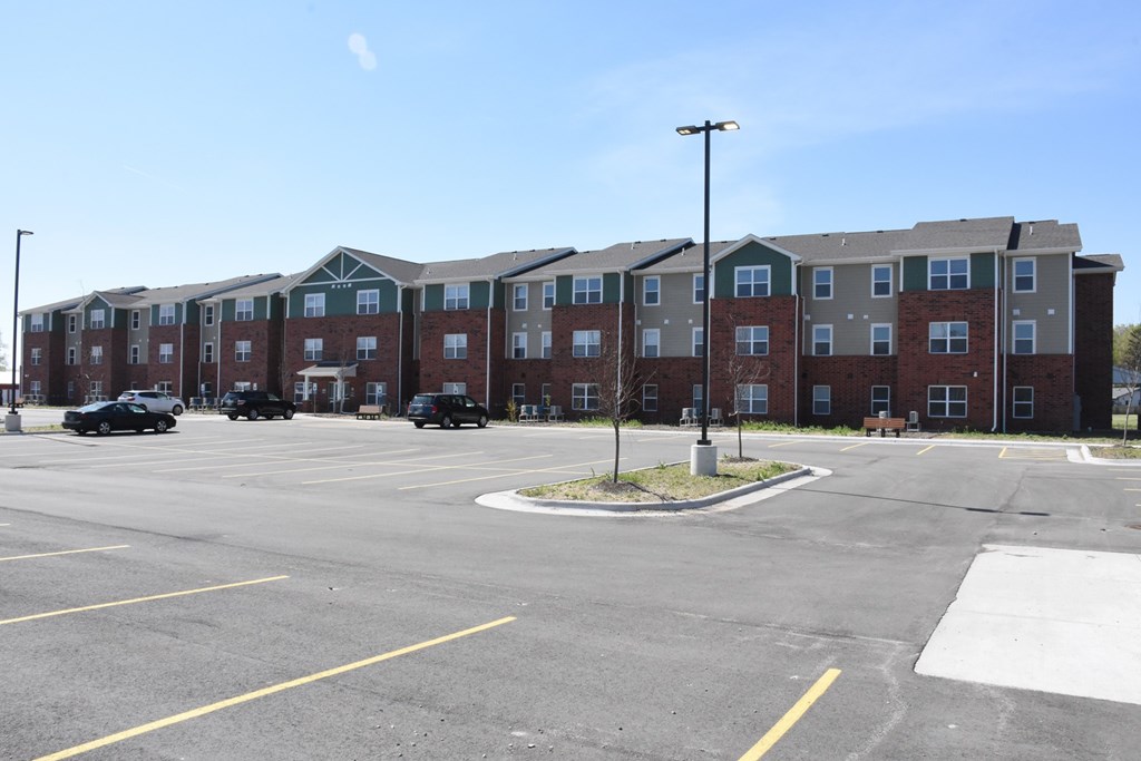 A parking lot in front of a large apartment complex.