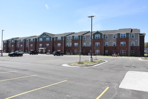 A parking lot in front of a large apartment complex.