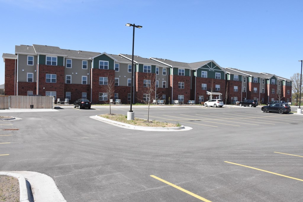 A parking lot in front of a large apartment complex.