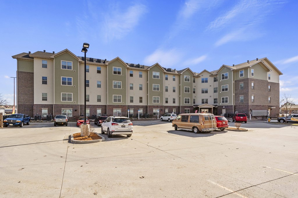 A parking lot in front of a large apartment building.