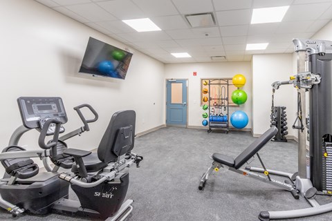a gym with exercise equipment and a tv in the corner of a room