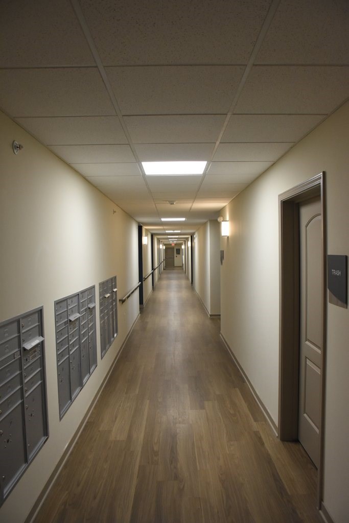 A long hallway with doors on the right and mailboxes on the left.