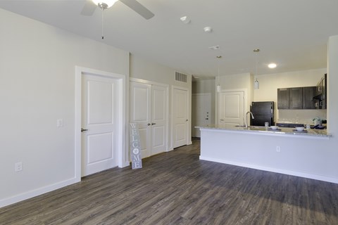 A spacious living room with a white reception desk and a wooden floor.