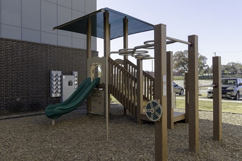 A playground with a green slide and a wooden structure.