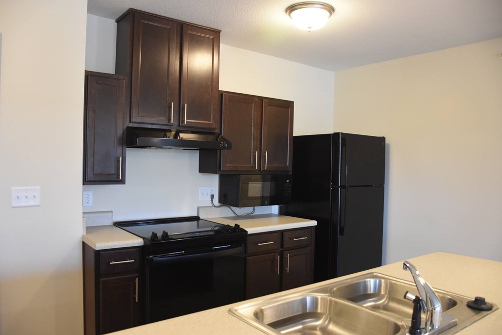 A kitchen with black appliances and brown cabinets.