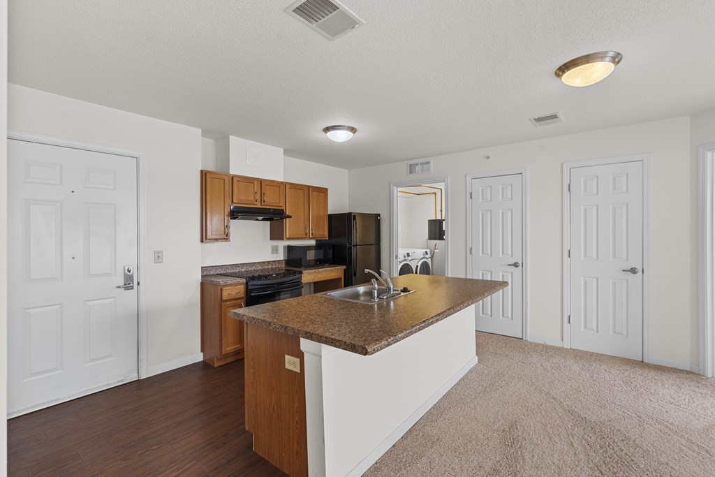 A kitchen with white walls and a brown island.