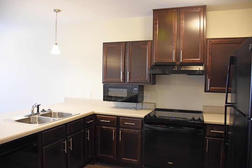 A kitchen with black appliances and brown cabinets.