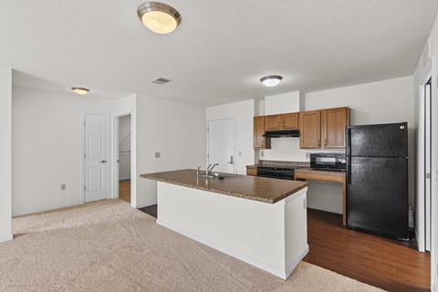 A kitchen with white cabinets and a black fridge.