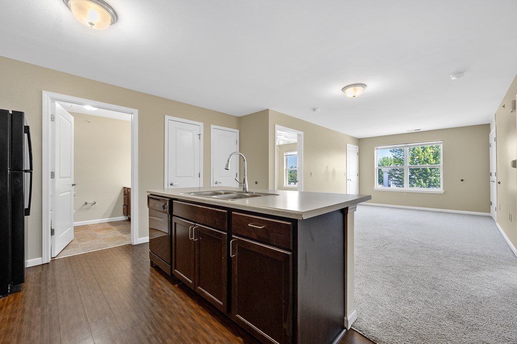 A kitchen with dark wood cabinets and a black refrigerator.