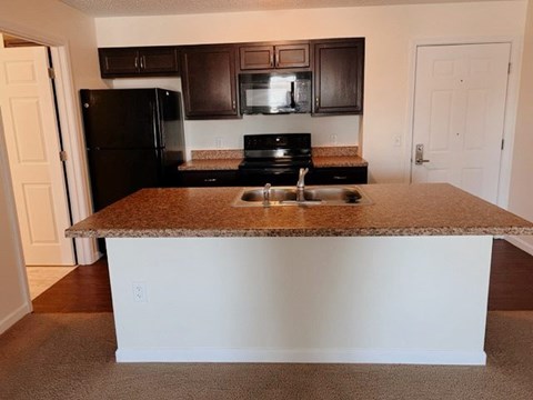 A kitchen with brown cabinets and a black refrigerator.