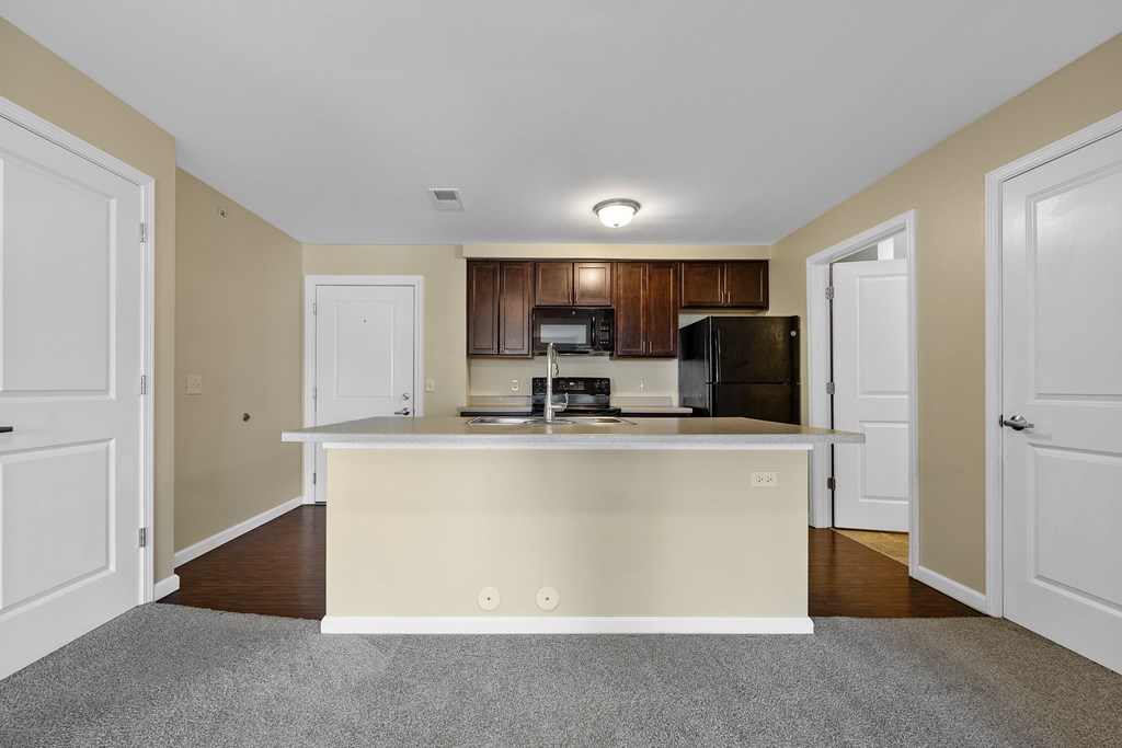 A kitchen with a white countertop and a black refrigerator.