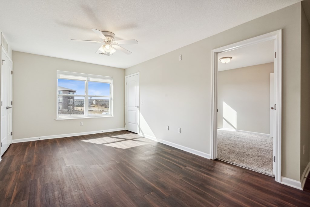 A room with a ceiling fan and a large window.