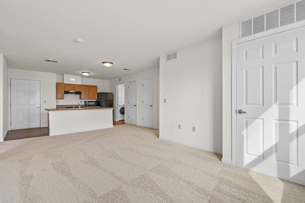 A spacious living room with a kitchen in the background.