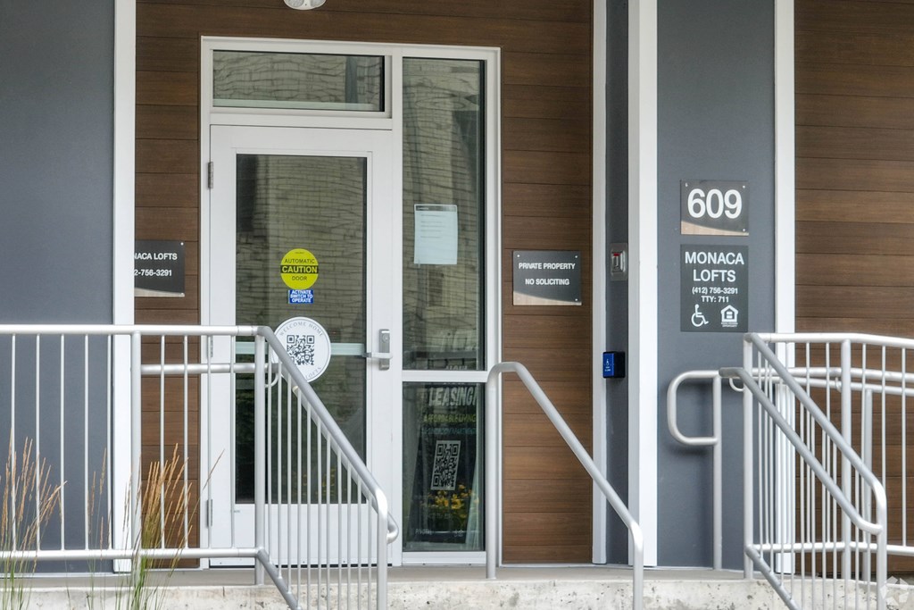The front door of a building with a sign that says "609 Monaca Lofts".
