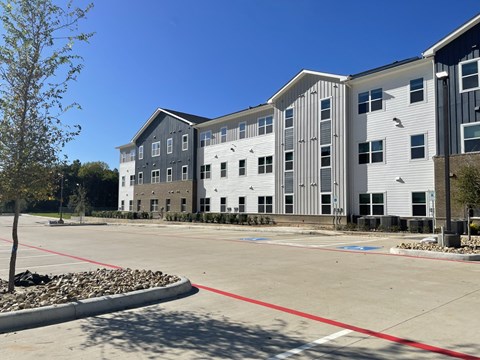 A parking lot in front of a multi-story building.
