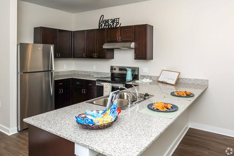 A kitchen with a granite countertop and a stainless steel refrigerator.