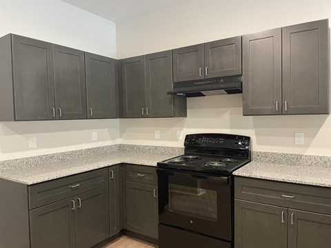 A kitchen with a black stove top oven and cabinets.