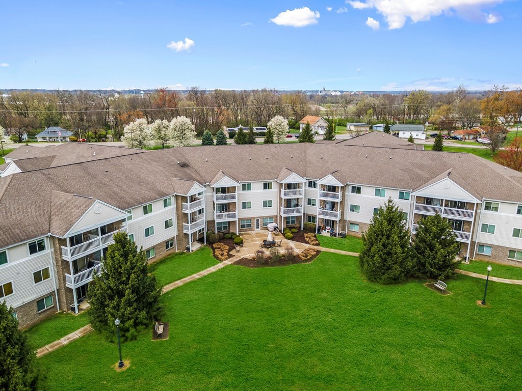 A large white building with a brown roof surrounded by a green lawn.