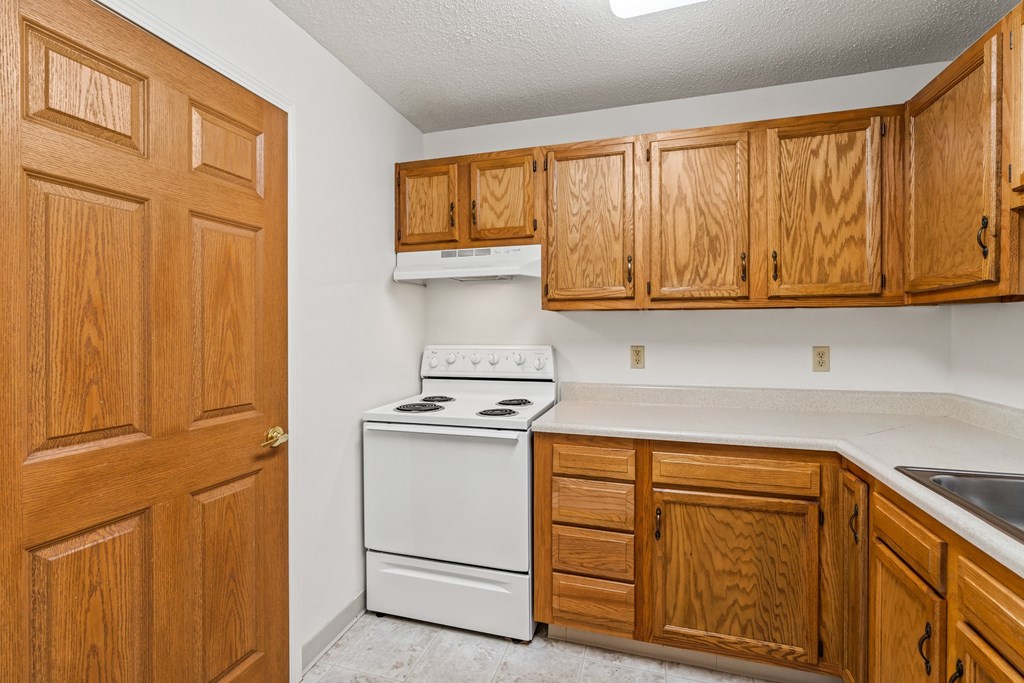 A kitchen with wooden cabinets and a white stove.