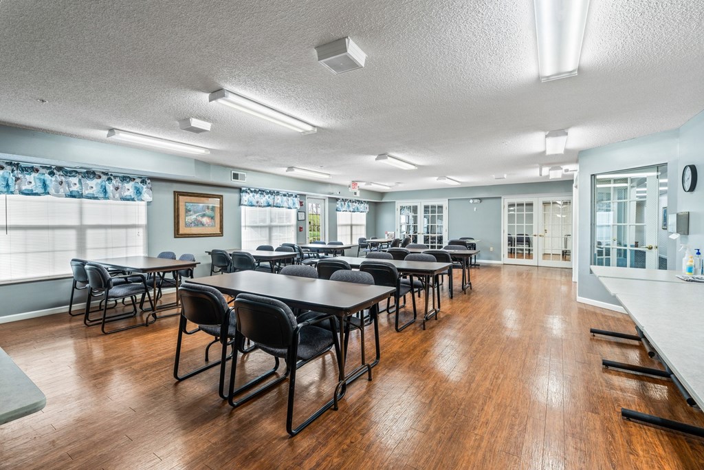 A room with tables and chairs and a painting on the wall.