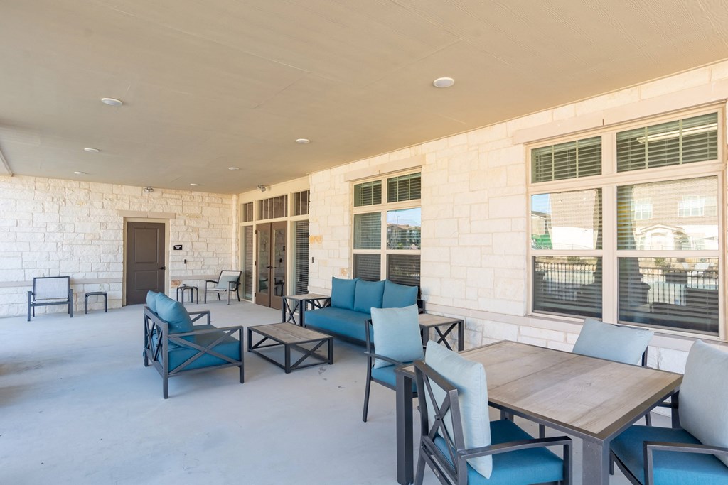 a patio with blue chairs and tables and windows