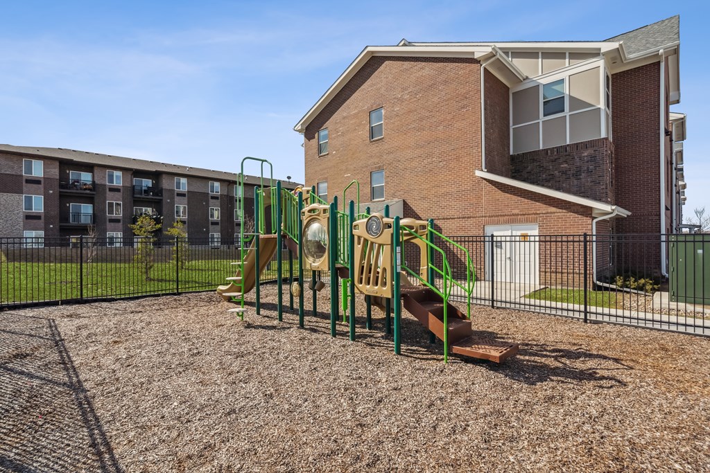 A playground with a slide and a building in the background.