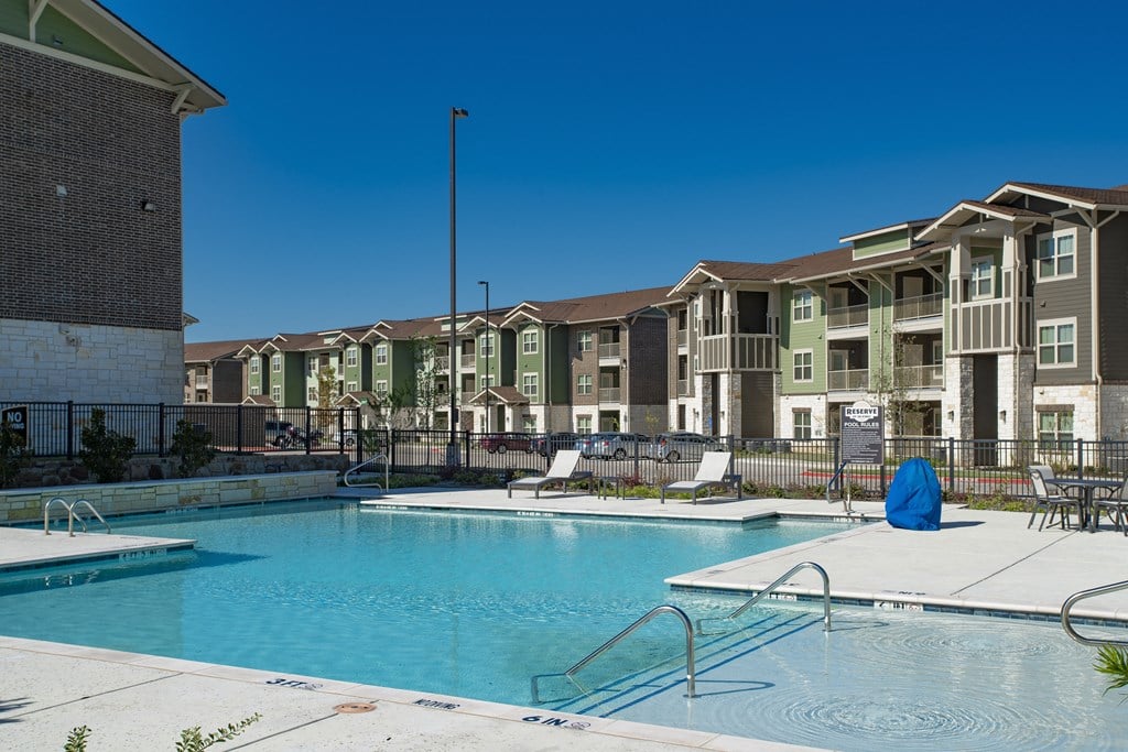 a swimming pool with an apartment building in the background