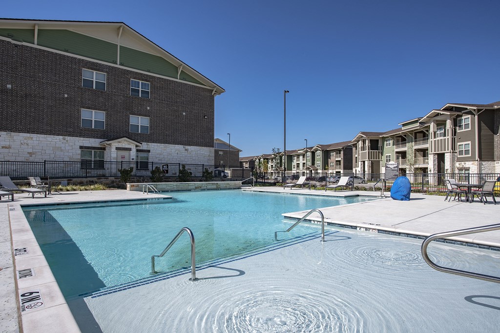 a swimming pool with an apartment building in the background