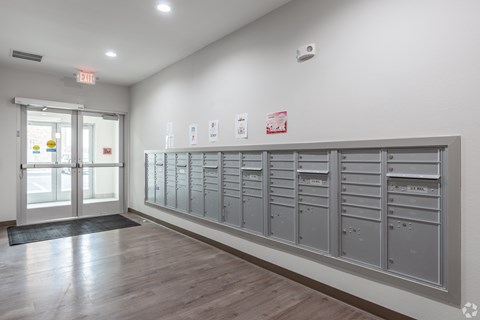 A long row of mailboxes are lined up on a wall.