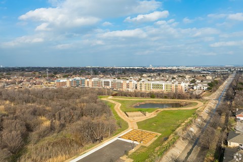 A large building complex is surrounded by trees and a road.