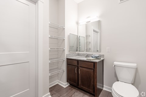 A white toilet sits next to a vanity with a mirror and a cabinet.