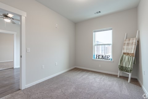 A room with a carpeted floor and a window with a view of a building outside.
