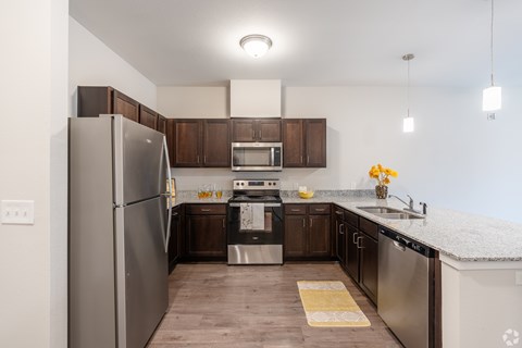 A kitchen with a refrigerator, oven, sink, and microwave.
