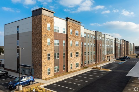 A long row of buildings with a blue car parked in front of the first one.