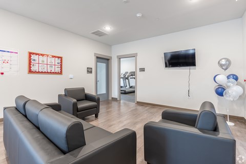 A living room with grey couches and a television on the wall.