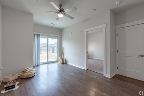 A spacious living room with a ceiling fan and sliding glass doors leading to a balcony.