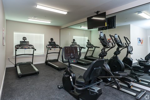 A gym room with treadmills, elliptical machines, and other exercise equipment.