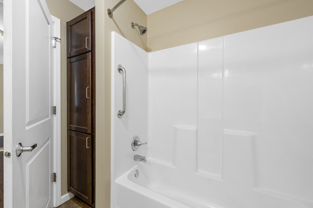 A white bathtub with a shower head and a brown door.