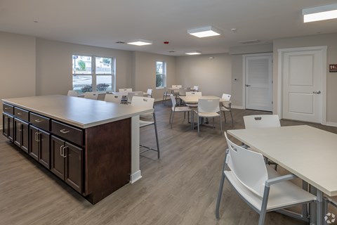 A room with tables and chairs and a brown counter.