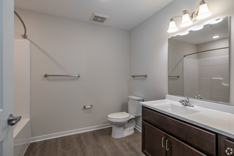 A bathroom with a toilet, sink, and mirror.