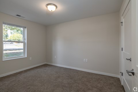 A room with a carpeted floor and a window letting in natural light.