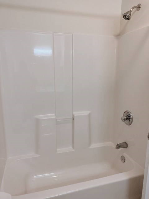 A white bathtub with a shower head and faucet.