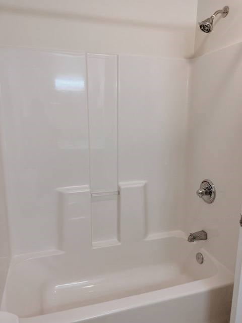 A white bathtub with a shower head and faucet.