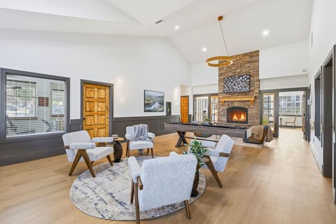 A living room with a stone fireplace and a large rug.
