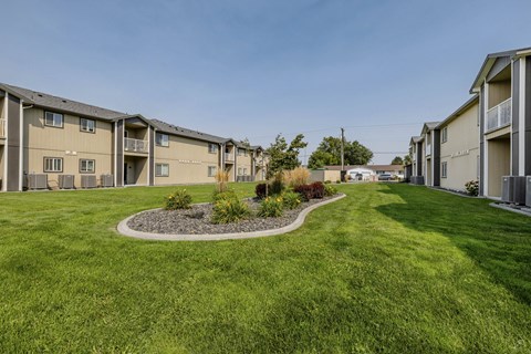 A row of apartment buildings with a green lawn in the foreground.