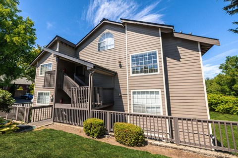 A house with a brown siding and a grey roof with a balcony.