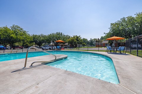 A large outdoor swimming pool with a slide and sunshades.