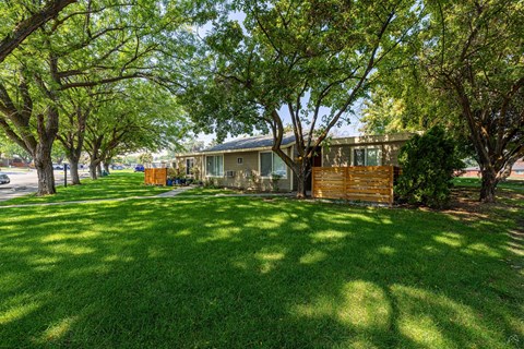 A house with a green lawn and trees in front.